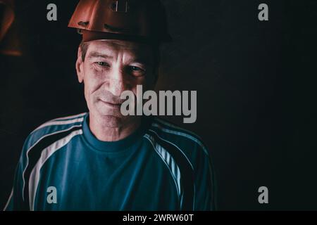 Porträt eines lächelnden alten Mannes in einem Bergarbeiterhelm Stockfoto