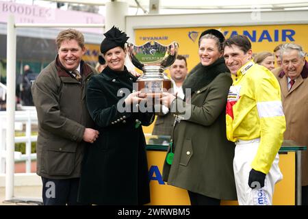 Trainer Dan Skelton (links), Ehefrau Grace Skelton und Jockey Harry Skelton (rechts) mit Ehefrau Bridget Andrews feierten mit Thron Trophäe nach dem Sieg in der Ryanair Turmjase am dritten Tag des Cheltenham Festivals 2024 auf der Cheltenham Racecourse. Bilddatum: Donnerstag, 14. März 2024. Stockfoto