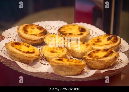 Verschiedene Pastel de Nata-Gebäckstücke, die elegant auf einer Spitze präsentiert werden Stockfoto