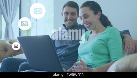Bild der digitalen Umschlagsymbole über dem kaukasischen Paar mit Laptop Stockfoto