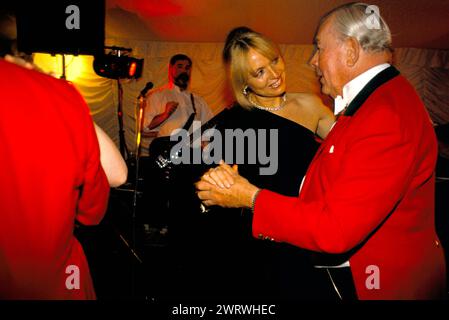 West Bagborough, Somerset, England 9. Mai 1997. Der jährliche Jagdball Quantock Staghounds feiert das Ende der Jagdsaison. Eine jüngere Frau tanzt mit einem älteren Mann, die Live-Band spielt auf der Bühne. Er trägt einen rosafarbenen Jagdmantel, was bedeutet, dass er ein Master of the Fox Hounds (MF) oder Staghounds ist. Der jährliche Ball findet im Bagborough House statt. 1990ER UK 1997 HOMER SYKES Stockfoto