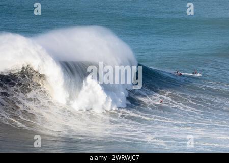 Europa, Portugal, Region Oeste, Nazaré, Surfer und Support Jet Skis auf riesigen Wellen in der Nähe von Praia do Norte während des Free Surfing Event 2022 Stockfoto