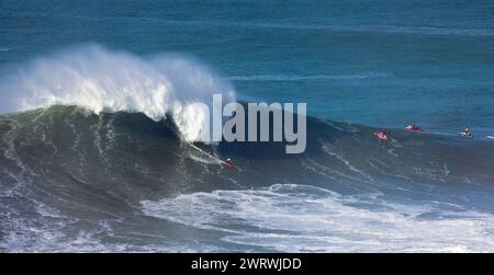 Europa, Portugal, Region Oeste, Nazaré, Surfer und Support Jet Skis auf riesigen Wellen in der Nähe von Praia do Norte während des Free Surfing Event 2022 Stockfoto