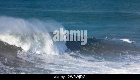 Europa, Portugal, Region Oeste, Nazaré, Surfer und Support Jet Skis auf riesigen Wellen in der Nähe von Praia do Norte während des Free Surfing Event 2022 Stockfoto
