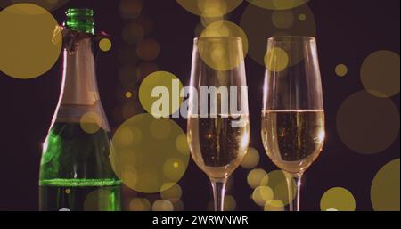 Bild von gelben Lichtflecken über zwei Gläsern und einer Flasche Silvester-Champagner Stockfoto