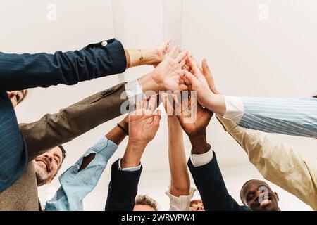 Vielfältige Geschäftsteams verbinden sich in einer hohen Geste mit fünf Händen und symbolisieren Einheit und Erfolg in einem Unternehmensumfeld. Stockfoto