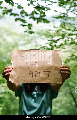 Eine Person, die ein Schild mit der Aufschrift „Rettet den Planeten“ hält. Stockfoto
