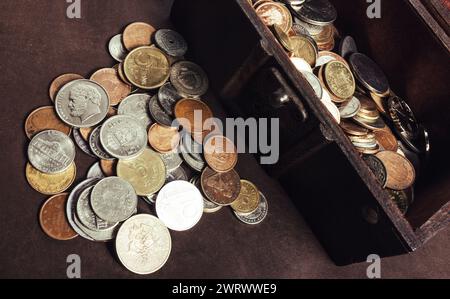 Foto einer hölzernen Schatzkiste oder Kiste mit Münzen auf der Tischoberfläche. Stockfoto