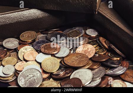 Foto von alten braunen antiken Büchern, die auf einem Stapel von Weltmünzen gestapelt sind. Stockfoto