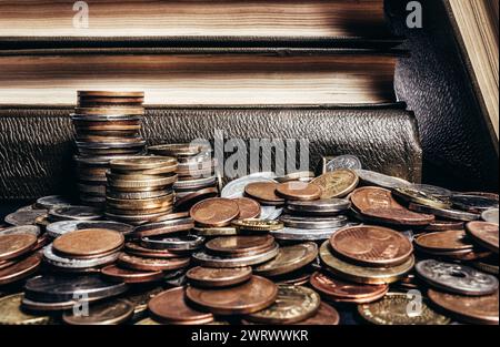 Foto von alten braunen antiken Büchern, die auf einem Stapel von Weltmünzen gestapelt sind. Stockfoto