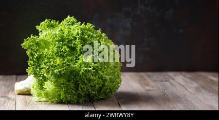 Ein großer Haufen frischer grüner Salatblätter auf einem Holztisch und mit dunklem Hintergrund. Gesunde Lebensmittel, Quelle von Mineralien und Vitaminen. Stockfoto