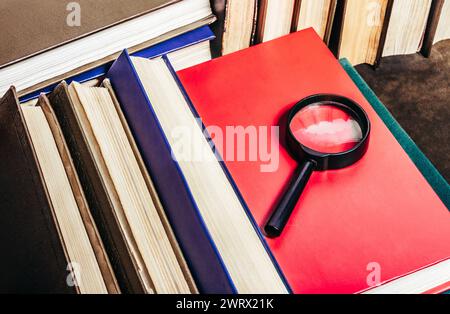 Foto von alten antiken Büchern, die auf Ledertischoberfläche liegen, mit Lupe. Stockfoto