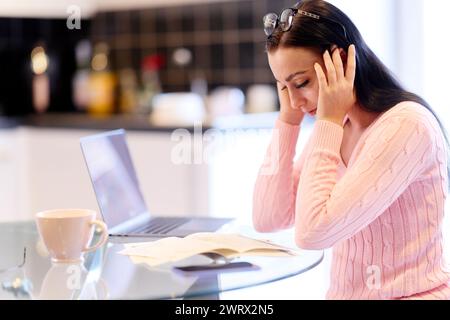 Frau, die zu Hause ihre Finanzen durchsucht Stockfoto