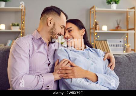 Lächelndes Paar, das einen liebevollen Moment auf dem Sofa zu Hause teilt Stockfoto