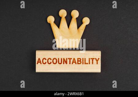 Konzept der Führungskraft. Auf einer schwarzen Oberfläche gibt es eine Holzkrone und einen Block mit der Inschrift "Verantwortlichkeit" Stockfoto