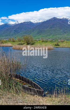 Blick auf Kerkini See im Norden Griechenlands ist mit traditionellen Holzmöbeln Fischerboot und Teil des schneebedeckten Mount Beles Stockfoto
