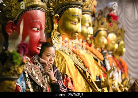 Eine Frau wird in Übereinstimmung mit den Idolen von Dipankara Buddha gesehen, die während eines Samyak Mahadan Festivals versammelt wurden. Das Samyak Mahadan Festival findet alle fünf Jahre in Lalitpur, Nepal, statt. Dieses Festival zeigt verschiedene große Idole von Dipankara Buddha. Gläubige aus allen Gesellschaftsschichten schenken den Gottheiten, ihren Hütern, Mönchen und den buddhistischen Gemeinschaften verschiedene Arten von Geschenken, einschließlich Geld und Essen. Der erste Samyak Mahadan soll 1015 n. Chr. in Nepal Sambat stattgefunden haben. Stockfoto