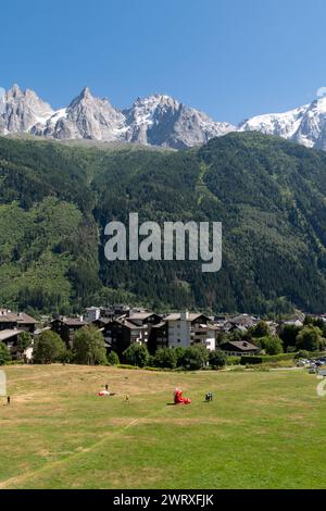 Gleitschirmflieger auf der Wiese mit der Alpenstadt und den Aiguilles von Chamonix im Hintergrund im Sommer, Chamonix, Haute Savoie, Frankreich Stockfoto