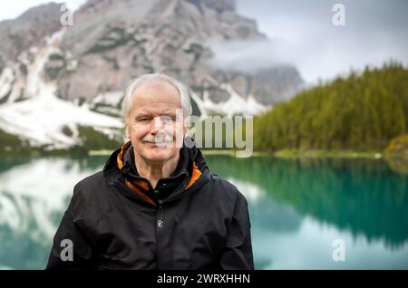 Senior Mann, der allein am wunderschönen Bergsee steht. Symbol für die aktive Einstellung im Alter. Stockfoto