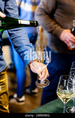 Ein Sommelier gießt während einer Weinprobe Sekt fachmännisch in ein Kristallglas und hebt die Finesse des Getränks hervor. Stockfoto
