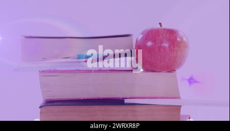 Bild von leuchtendem Licht über Apfel auf einem Stapel Bücher Stockfoto