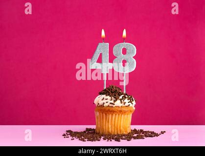 Geburtstagsfeier mit Kerze Nummer 48 - Schokoladen-Cupcake auf rosa Hintergrund Stockfoto