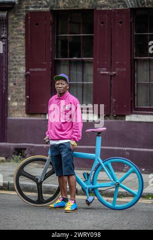 Junger Hipster, der mit festem Fahrrad auf der Straße in Bricklane East London, Großbritannien, steht Stockfoto