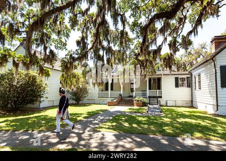 Ein Freiwilliger, der als Kolonialsoldat gekleidet ist, geht am Haupthaus der Charles Pinckney SNEE Farm Plantage an der Charles Pinckney National Historic Site in Mt Pleasant, South Carolina vorbei. Pinckney, ein Gründervater der Vereinigten Staaten, war Delegierter des Verfassungskonvents, wo er an der Ausarbeitung der Verfassung der Vereinigten Staaten mitwirkte. Stockfoto