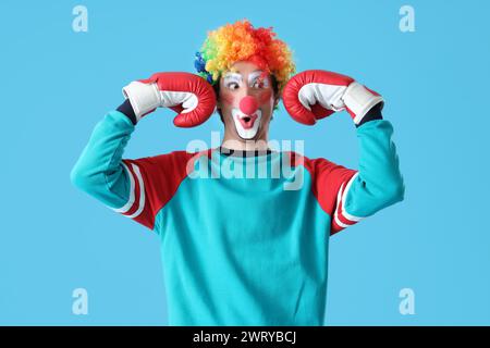 Porträt eines überraschten Clowns mit Boxhandschuhen auf blauem Hintergrund. Aprilfeier zum Narrentag Stockfoto