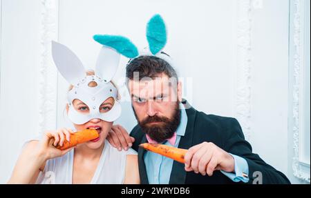 Respektieren Sie Traditionen. Frohe ostertage. Kaninchen Mann und Mädchen essen Karotten. Niedliche Häschen Mode formeller Anzug Smoking. ostern feiern. Büroparty Stockfoto