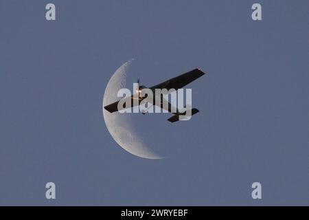 Santiago, Metropolitana, Chile. März 2024. Ein kleines Flugzeug fliegt vor der Mondsichel in Santiago, Chile. (Kreditbild: © Matias Basualdo/ZUMA Press Wire) NUR REDAKTIONELLE VERWENDUNG! Nicht für kommerzielle ZWECKE! Stockfoto