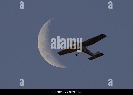 Santiago, Metropolitana, Chile. März 2024. Ein kleines Flugzeug fliegt vor der Mondsichel in Santiago, Chile. (Kreditbild: © Matias Basualdo/ZUMA Press Wire) NUR REDAKTIONELLE VERWENDUNG! Nicht für kommerzielle ZWECKE! Stockfoto