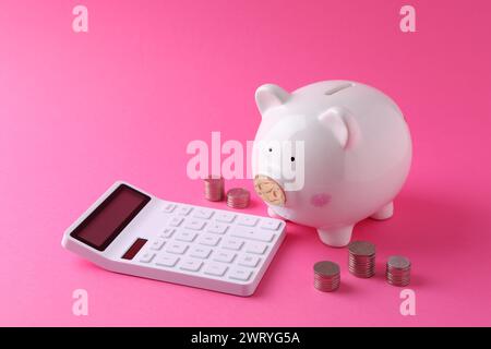 Finanzielle Einsparungen. Schweinebank, Münzen und Taschenrechner auf rosafarbenem Hintergrund Stockfoto