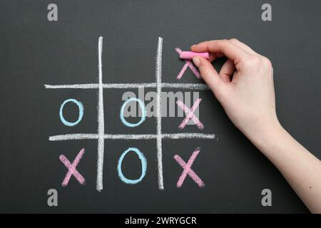 Frau spielt Tic Tac Toe auf Tafel, Nahaufnahme Stockfoto