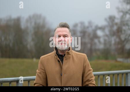 Porträt eines Mannes mittleren Alters mit grauem Haar und grauem Bart im Winter oder Frühling in einem Park Stockfoto