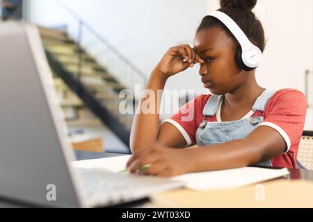 Das afroamerikanische Mädchen konzentriert sich auf ihre Schularbeit, mit ihrem Laptop zu Hause Stockfoto