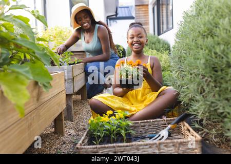 Ein junges afroamerikanisches Mädchen hilft bei der Gartenarbeit und lächelt hell Stockfoto