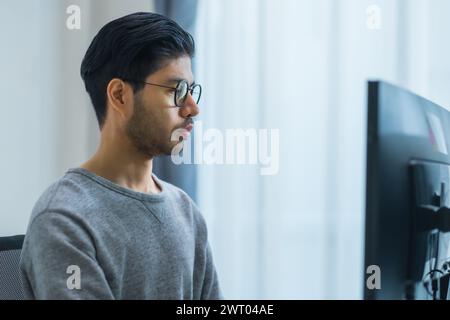 Asiatischer Ingenieur, der die Software-Daten vor dem Computermonitor im Büro codiert Stockfoto