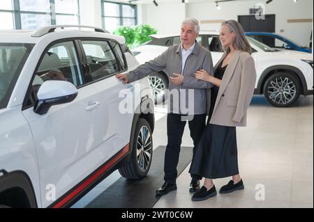 Ein älteres kaukasisches Paar wählt ein neues Auto in einem Autohändler. Stockfoto