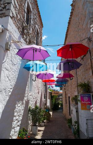 Enge Gasse mit einer Reihe von bunten schwimmenden Sonnenschirmen, Altstadt, Areopoli, Areopolis, Tsimova, Itylo, Anatoliki Mani, Mani, Laconia Stockfoto