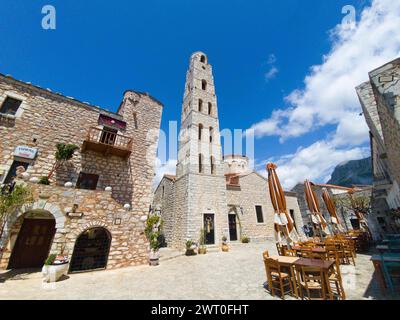Alter Steinturm auf einem Platz mit offenen Sonnenschirmen und blauem Himmel, Taxiarchis-Kirche, Altstadt, Areopoli, Areopolis, Tsimova, Itylo, Anatoliki Mani, Mani Stockfoto