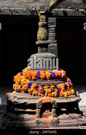 Eine Stupa mit einem bunten Blumenkranz in einem Tempelbereich, Kathmandu Valley, Kathmandu, Nepal Stockfoto