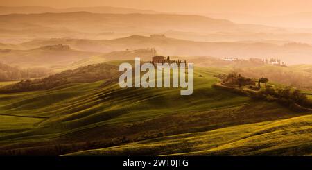 Eine wunderschöne nebelige toskanische Landschaft mit einer Villa auf einem Hügel und Nebel im Hintergrund bei Sonnenuntergang. Ein wunderschönes Reiseziel in Italien. Stockfoto