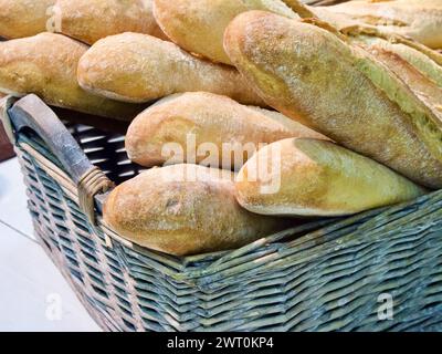 Frisch gebackene Vollkorn-Baguettes aus biologischem Anbau in gewebtem Brotkorb. Stockfoto