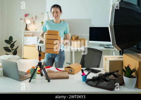 Eine junge Frau, Eigentümerin eines kleinen E-Commerce-Unternehmens, verpackt Artikel in den Briefkasten und bereitet sich darauf vor, sie auf einen Tisch zu liefern Stockfoto