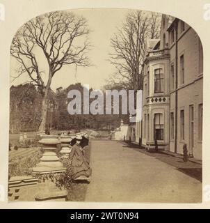 Frau außerhalb des Anwesens. Wahrscheinlich Frances Elizabeth Jocelyn, Viscountess Jocelyn, Fotografin (Britin, 1820–1880), etwa 1850–1860, Eine Frau, die außerhalb des Sandringham House in Norfolk stand. Sie hält einen Regenschirm und steht am Rand eines Feldes oder Gartens. Eine Reihe von Urnen auf Sockeln säumt den Weg neben ihr. Dieses Anwesen gehörte von 1843 bis 1862 Frances Elizabeth Jocelyns Bruder Charles Cowper. Stockfoto