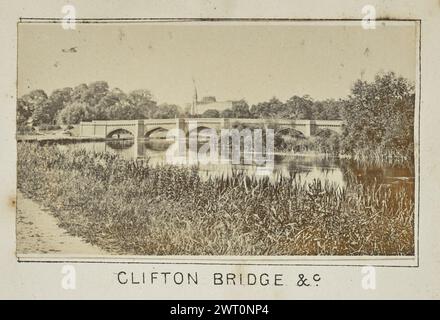 Clifton Bridge &c... Henry W. Taunt, Fotograf (Britisch, 1842 - 1922) 1897 eines von zwei Fotos mit Tippkarten, die eine gedruckte Karte von Little Wittenham, Dorchester, Warborough und der Umgebung entlang der Themse illustrieren. Das Foto zeigt einen Blick auf die Clifton Hampden Bridge von einem unbefestigten Fußweg, der parallel zum Fluss verläuft. Der Turm und das Dach der Kirche St. Michael und alle Engel sind über der Brücke zu sehen. (Recto, Mount) unten in der Mitte, unter dem Bild, in schwarzer Tinte gedruckt: 'CLIFTON BRIDGE &c' Stockfoto