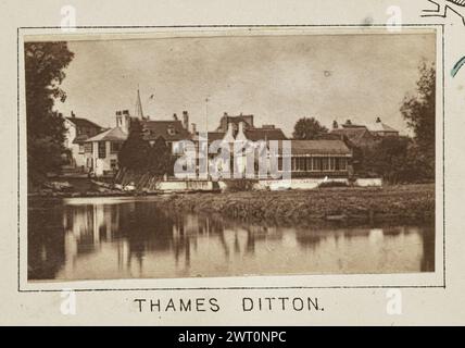 Thames Ditton. Henry W. Taunt, Fotograf (britischer Fotograf, 1842–1922) um 1886 eines von drei Fotos, die eine gedruckte Karte von Kingston und der Umgebung, einschließlich Hampton Court Park und Bushy Park, entlang der Themse illustrieren. Das Foto zeigt einen Blick auf das Swan Hotel am Flussufer in Thames Ditton von der anderen Seite des Wassers. An der Bootsanlegestelle des Hotels befinden sich mehrere Boote, die an den Docks befestigt sind, und zwei Männer stehen oben auf der Treppe, die zum Wasser führt. (Recto, Mount) unten in der Mitte, unter dem Bild, in schwarzer Tinte gedruckt: „THAMES DITTON“. Stockfoto