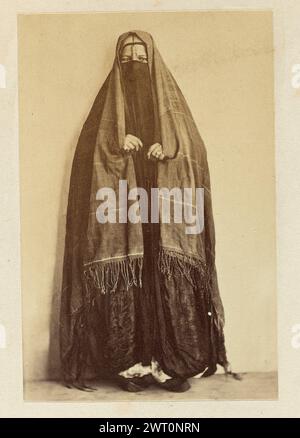 Porträt einer Frau. Wilhelm Hammerschmidt, Fotograf (deutsch, geb. Preußen, gestorben 1869) 1860er Jahre Eine hellhäutige Frau, die einen dunklen zweiteiligen Niqab mit Metallverzierung an der Nasenschnur trägt. An ihren Händen trägt sie Ringe und hält sich an den Kanten ihres Kopfschals fest. Sie posiert in einem leeren Innenraum vor einer weißen Wand. Stockfoto