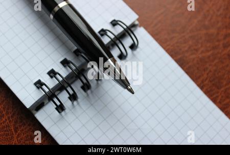 Schreibstift auf Einem Ordner mit karierten Notizen auf Einem Lederordner Stockfoto